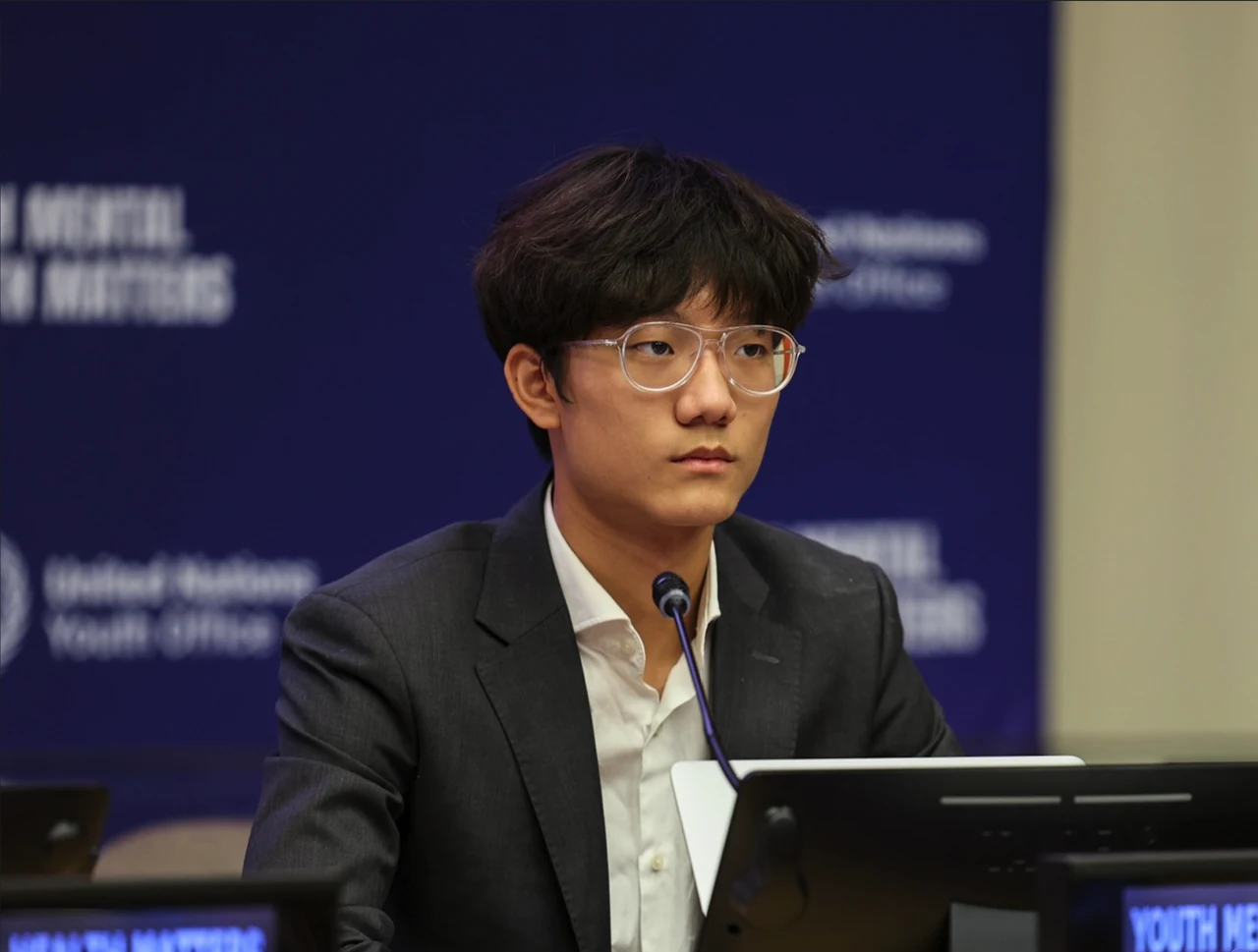 Steven Chen seated at a microphone, wearing a dark jacket and glasses, with a blue conference backdrop.