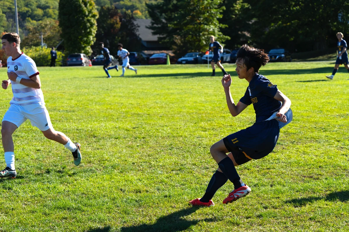 A soccer player in a blue number 11 uniform runs on a grass field during a match.